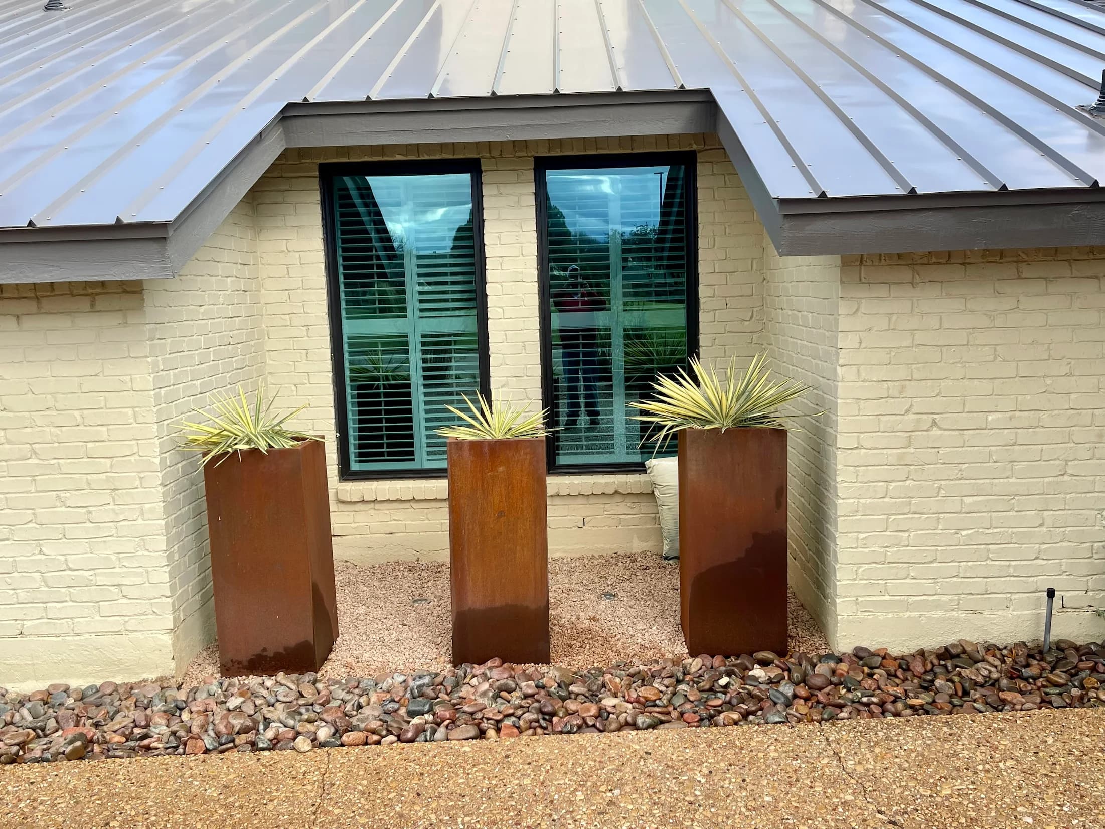 Modern planters set in a finished river-rock landscape bed